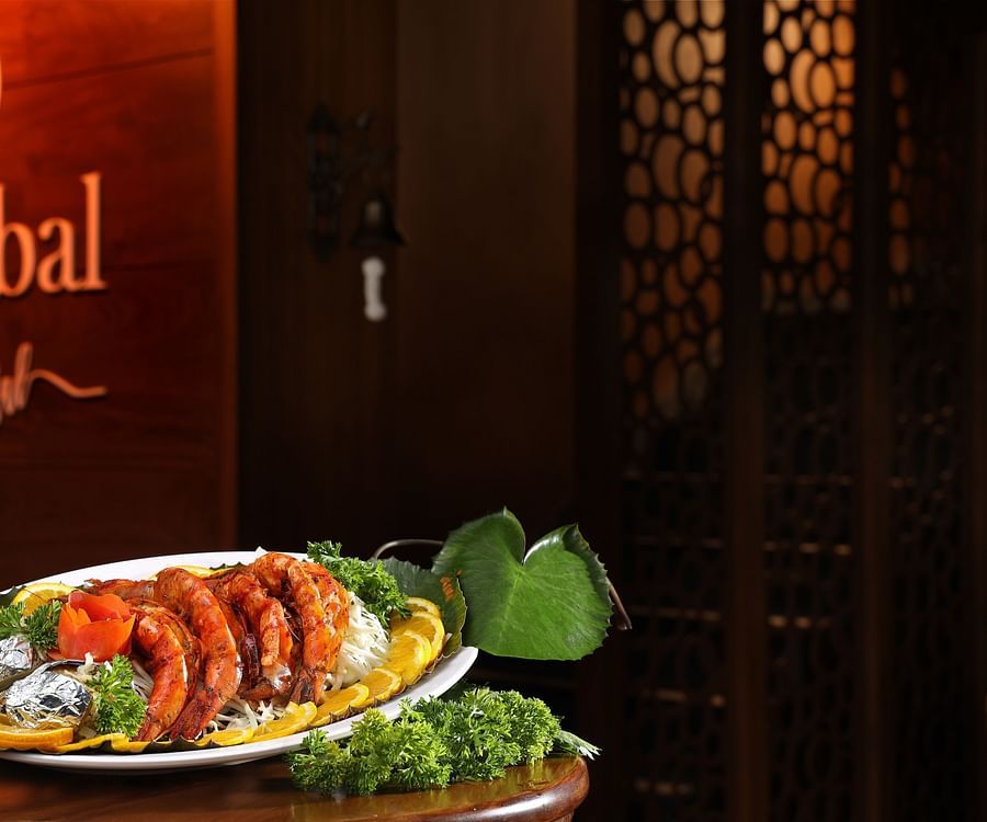 A platter of seafood placed on the table with the name of Aambal Restaurant highlighted on the wall in the background at Uday Backwater Resort