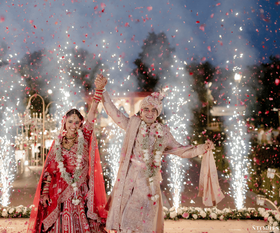 Bride and groom making a grand wedding entry with fireworks at Umaid Palace.