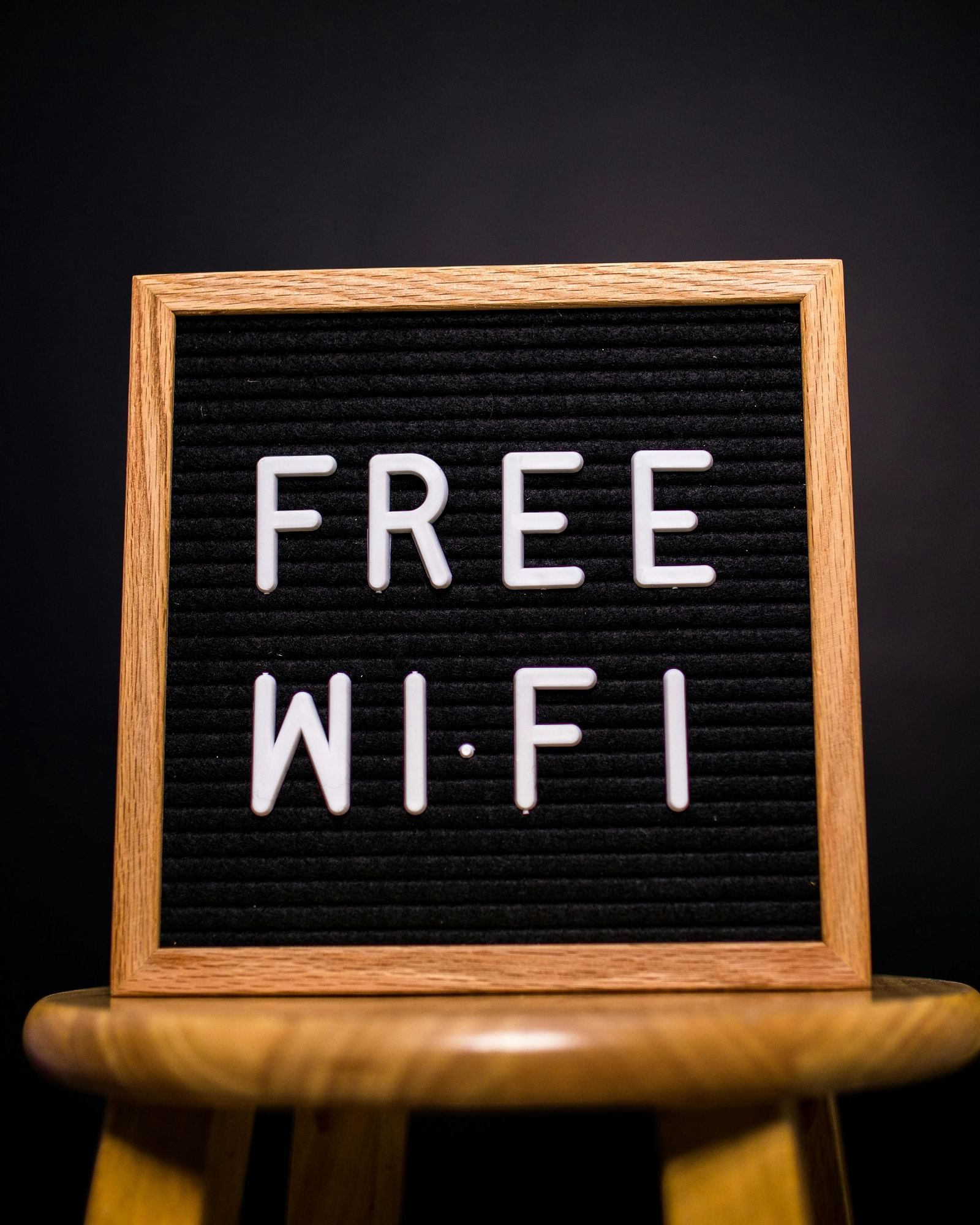A small chalkboard sign on a wooden stand displaying FREE WI-FI in white letters against a black background.