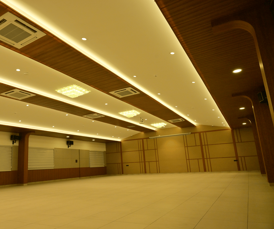 Spacious banquet hall at Bhavanis Vista By Icon Hosur with layered false ceiling, cove lighting, and mirrored side wall.
