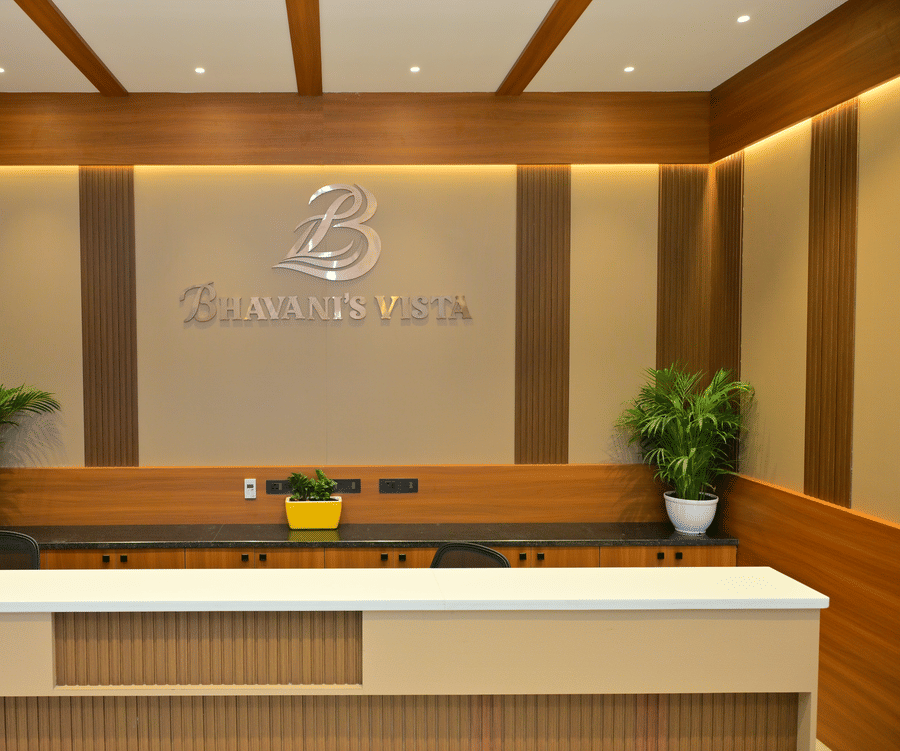 Reception desk of Bhavanis Vista By Icon featuring a counter, signage, and potted plants.