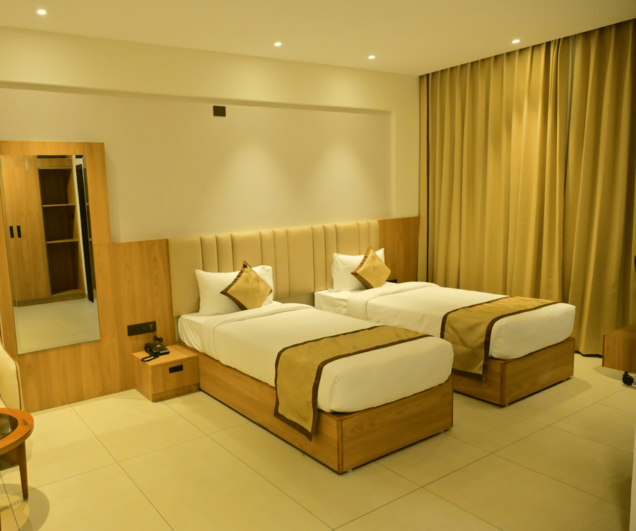 Bedroom of Bhavanis Vista By Icon featuring twin beds, a headboard, an armchair, and a door.