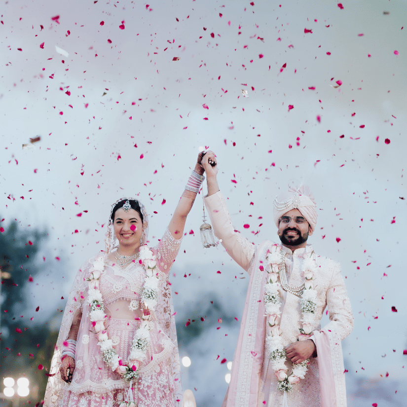 Bride and groom celebrating with confetti during a wedding ceremony at Umaid Palace.