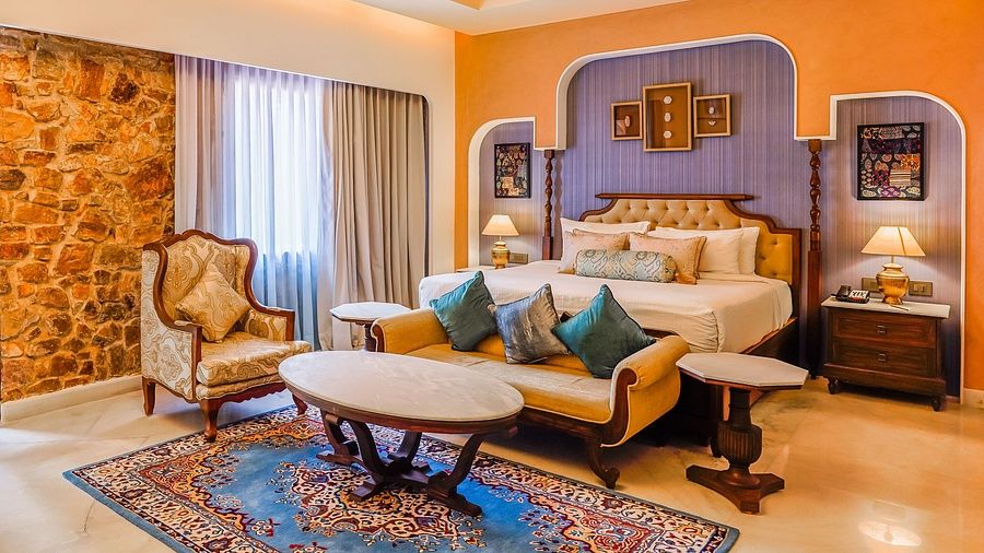 A spacious and heritage style Kumbha Villa featuring a king size bed, traditional decor, vintage furniture, and large windows with natural light at a luxury resort.