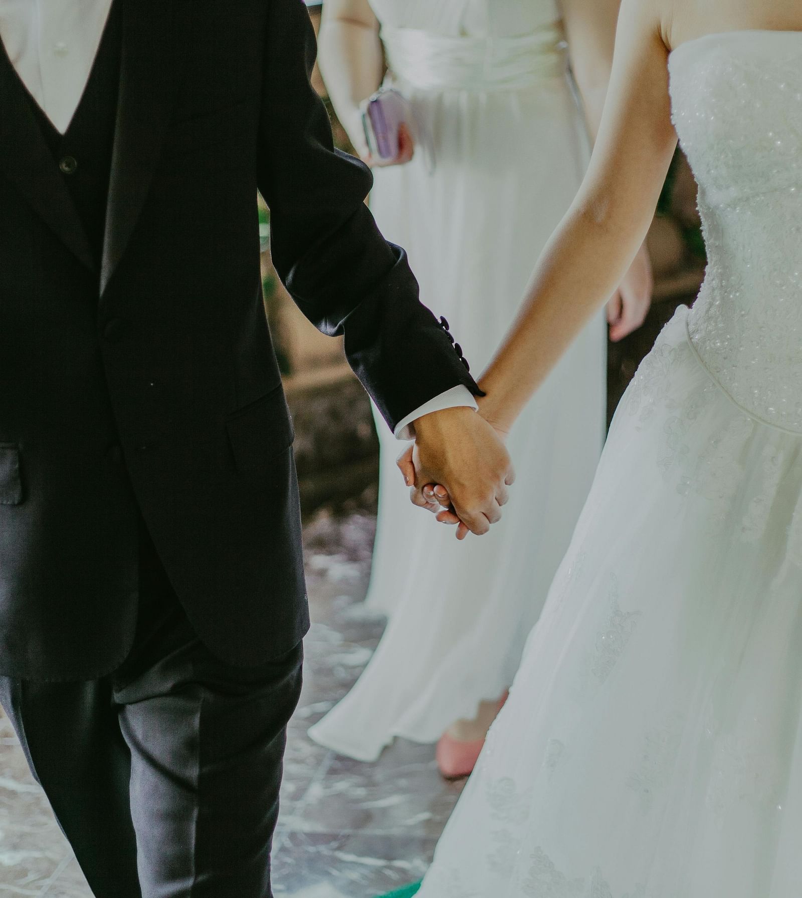 A married couple holding hands and walking out of the church.