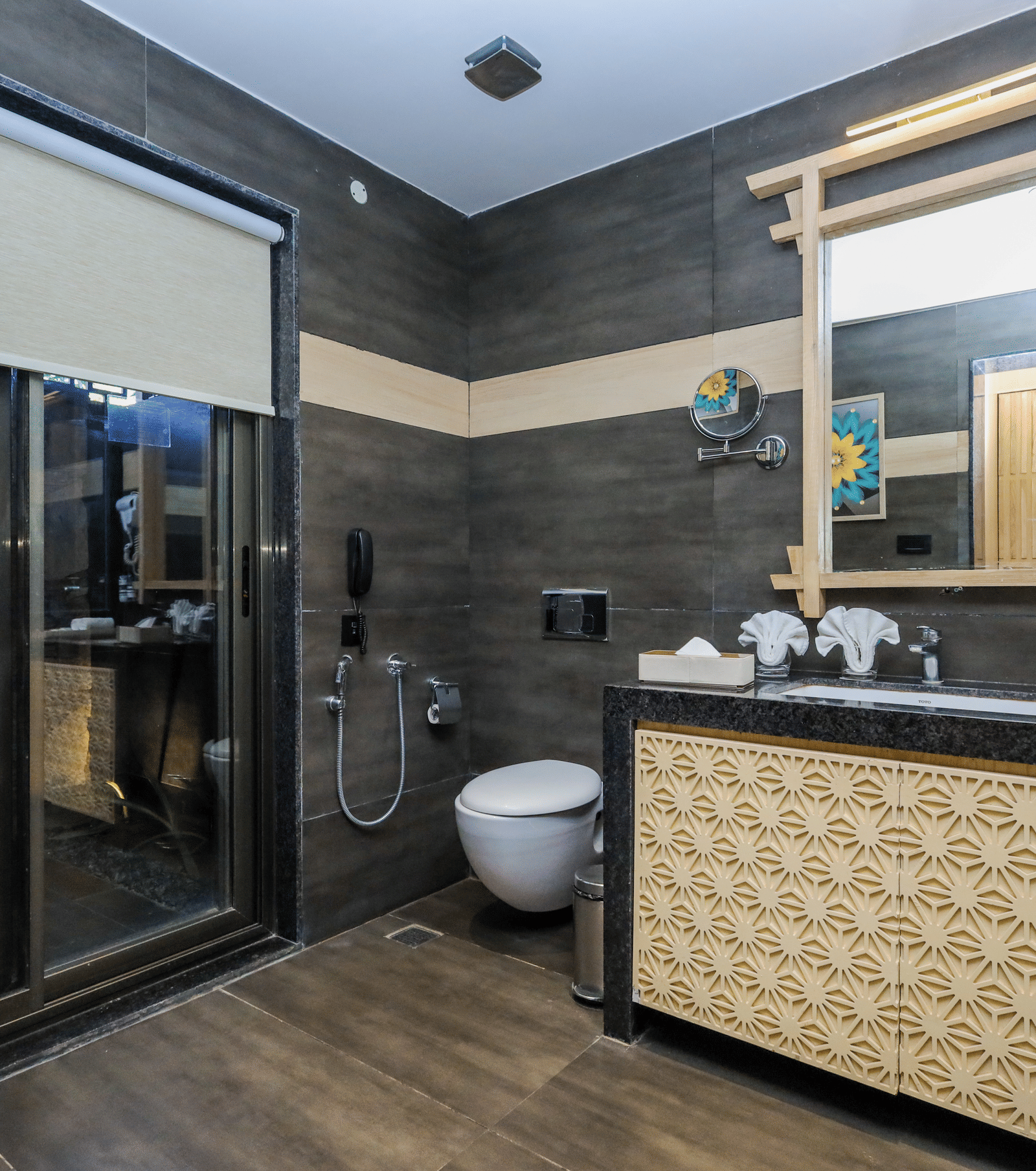 A bathroom with a counter, mirror, sink, toilet and glass shower enclosure at Ananta Spa & Resort, Jaipur.