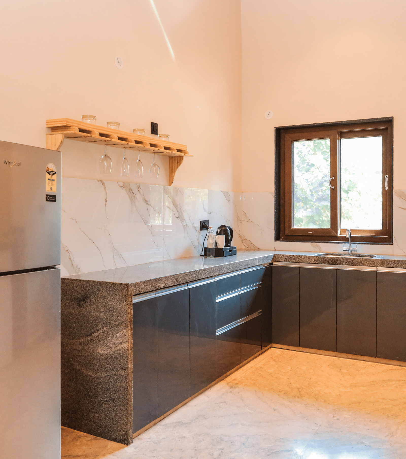 A kitchen shows a refrigerator, a counter with cabinets, a sink, a stove and a window above the workspace at Ananta Spa & Resort, Jaipur.