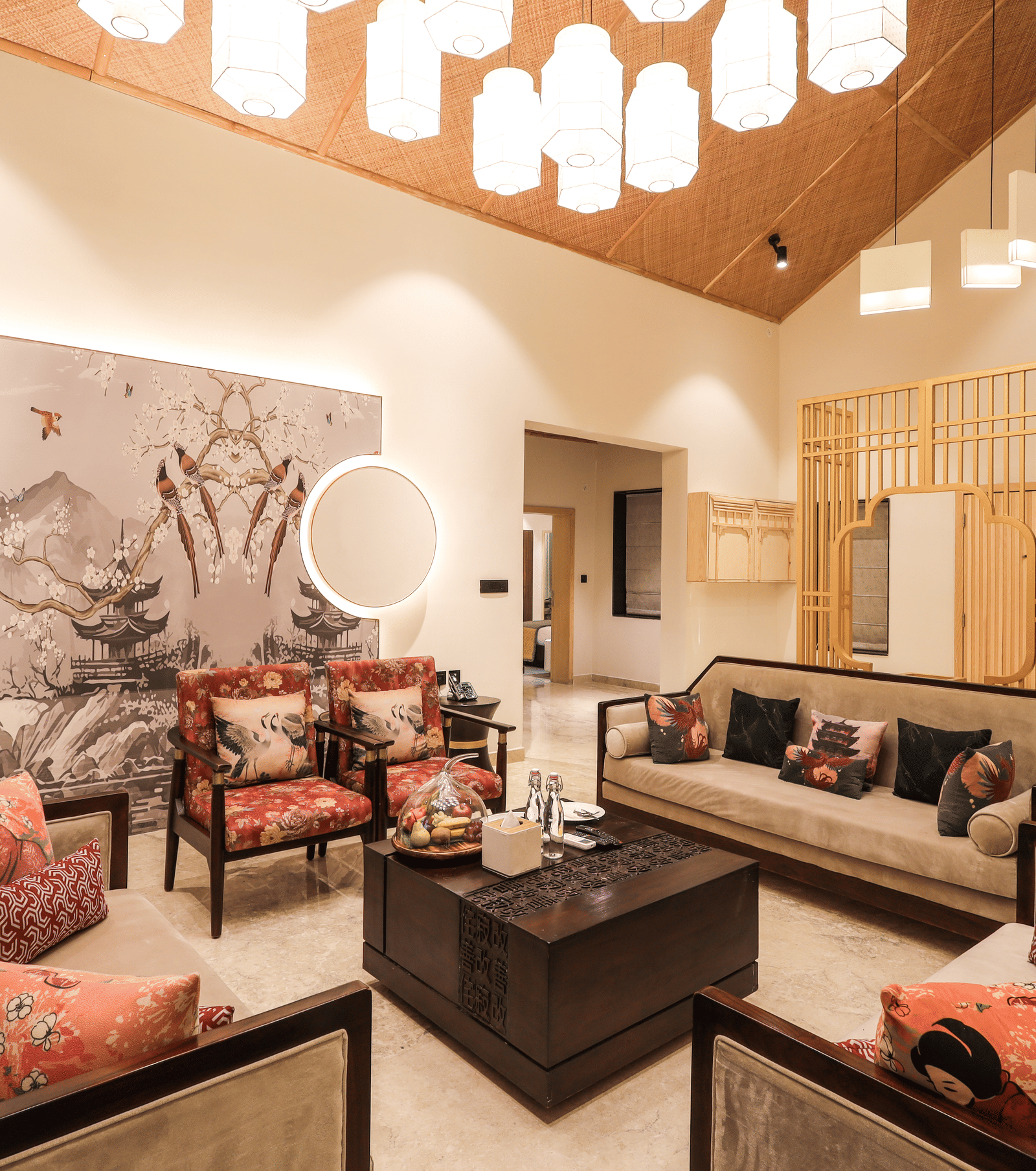 A room shows a sofa set with a centre table, chairs on both sides, a wall artwork behind the seating and cabinets to one side at Ananta Spa & Resort, Jaipur.