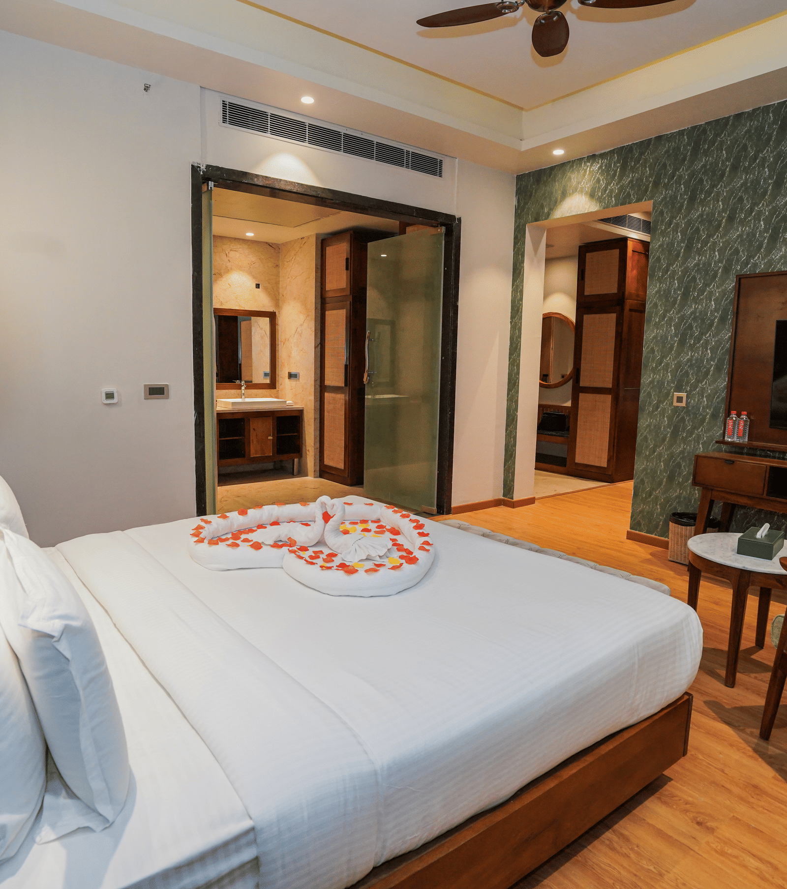 A room with a flower-adorned bed, TV, and a view into the bathroom at Pushkara Resort & Spa.