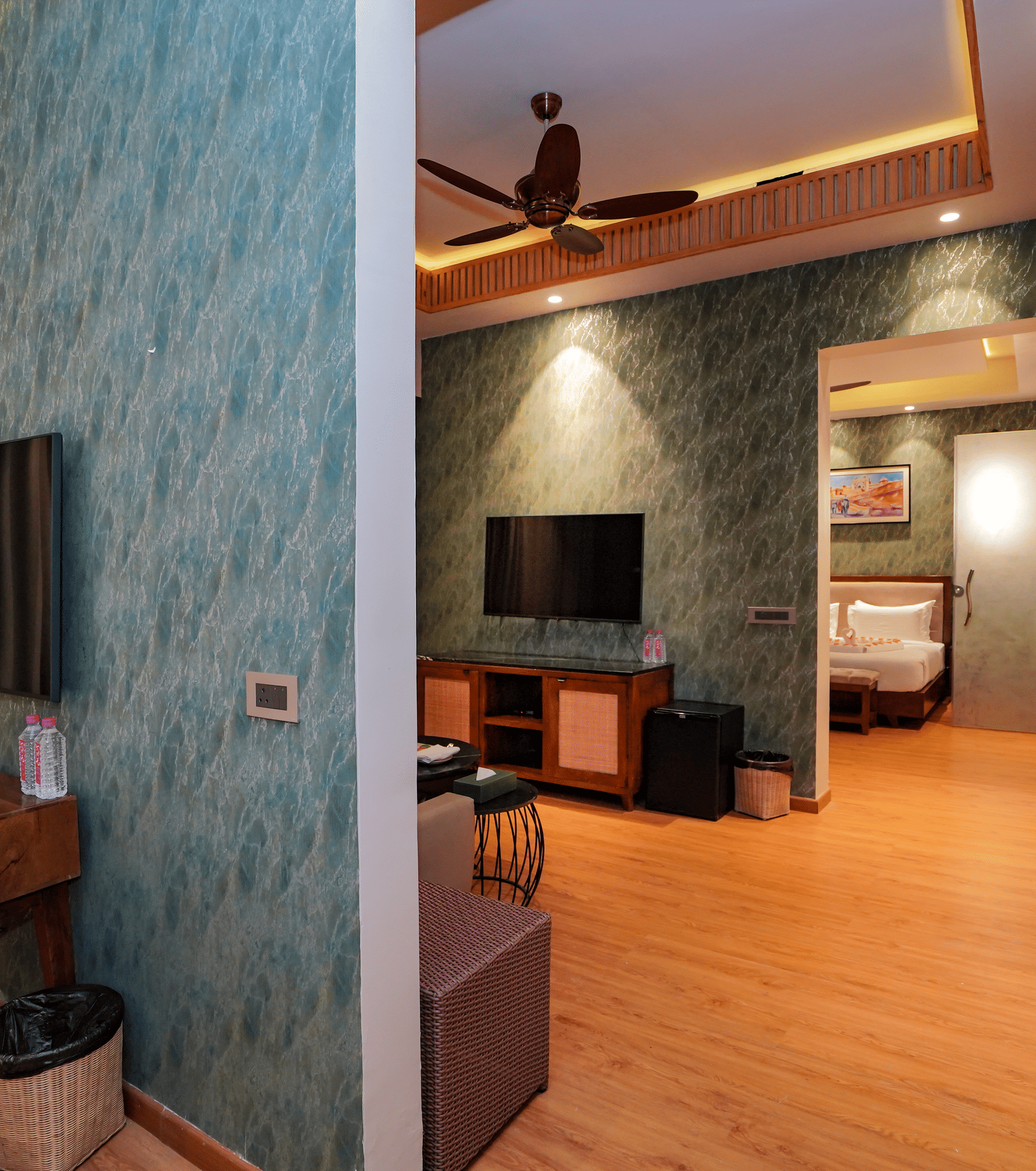 A stylish suite interior with patterned wallpaper, a desk, and a view into the separate living area at Pushkara Resort & Spa.