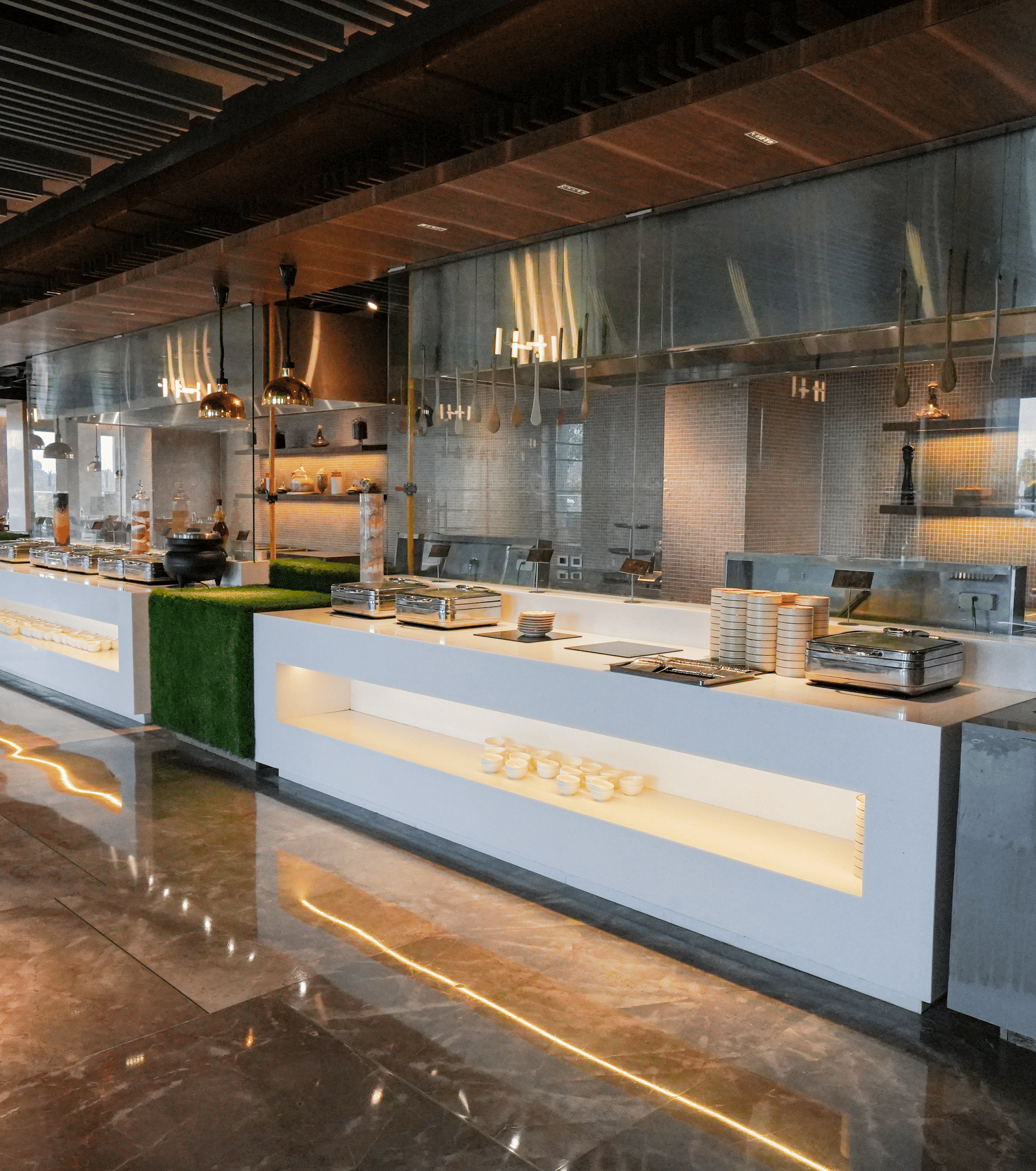 A bright, modern open kitchen and buffet serving area with sleek stainless steel accents at Pushkara Resort & Spa.