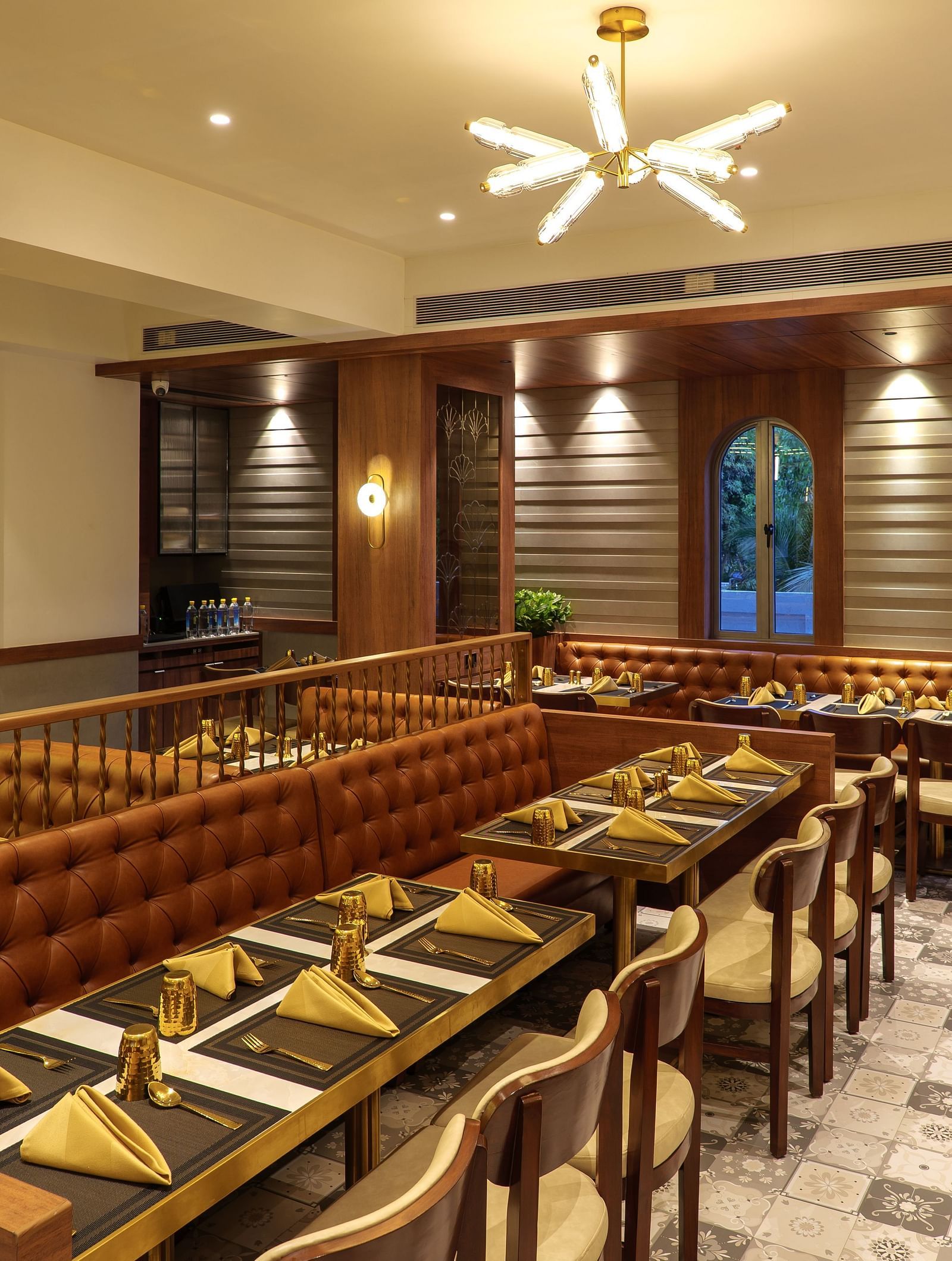 A warmly lit restaurant area features multiple tables set for dining, wooden accents, and decorative wall panels - Melior Inn