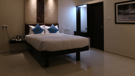 A well-appointed guest room with a queen bed, ambient recessed lighting, and a framed black-and-white photo on the wall at The Bull Boutique Hotel.