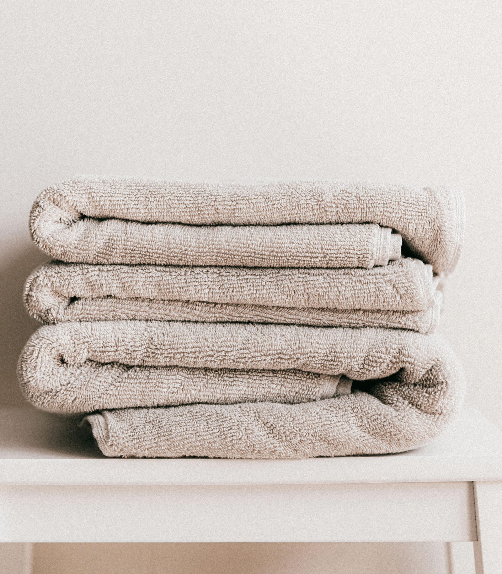 image of clean white coloured towels neatly folded and kept on a white stool