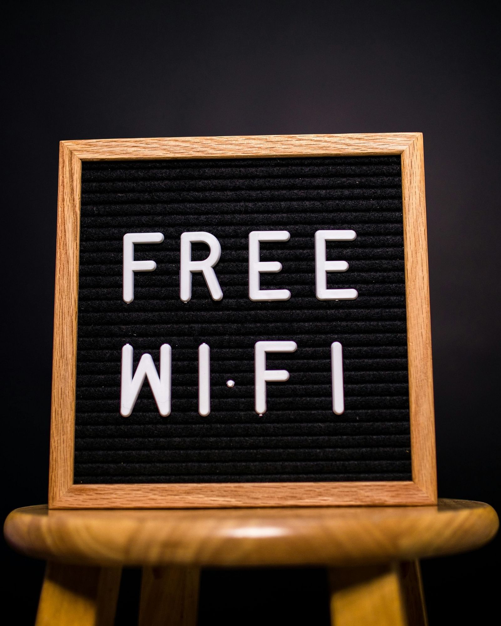 A small chalkboard sign on a wooden stand displaying FREE WI-FI in white letters against a black background.