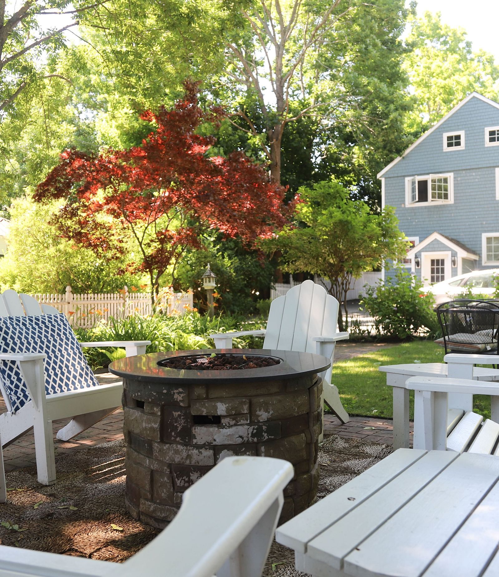 Outdoor garden seating area with white Adirondack chairs and a view of Hartstone Inn in the background.