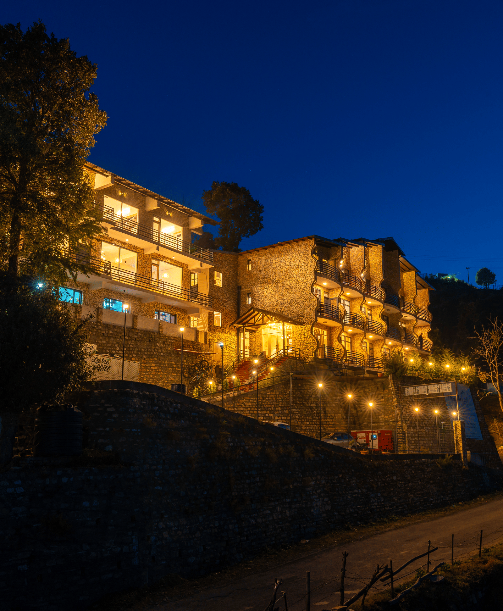 Himalayas Resort By The Lake Hill, Mukteshwar beautifully lit up against a dark blue night sky.