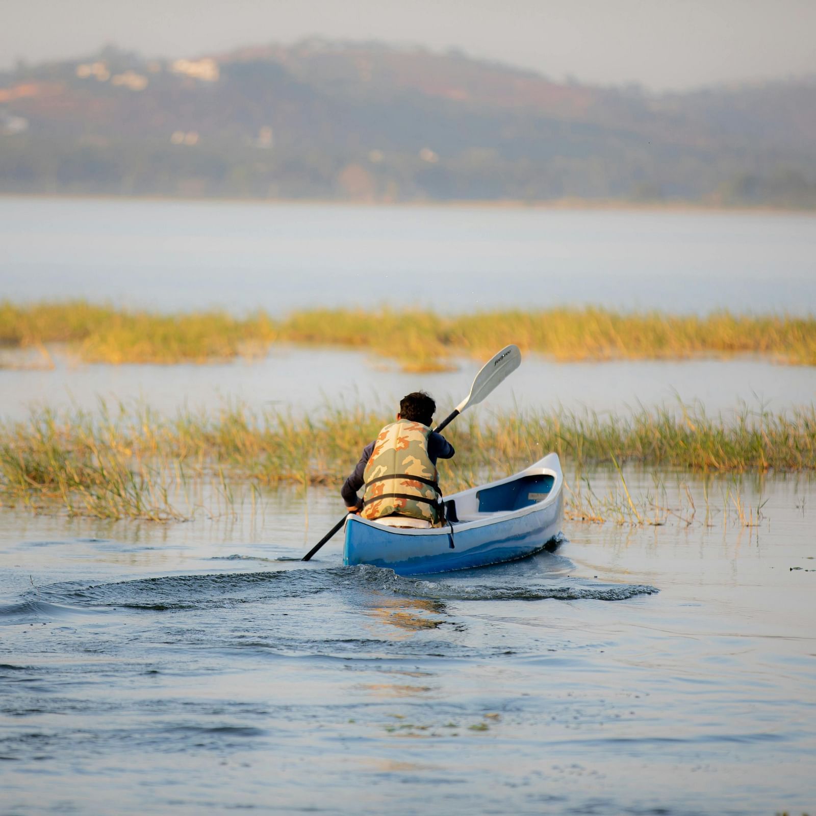 An image of a person boating through a lake with the backdrop of mountains