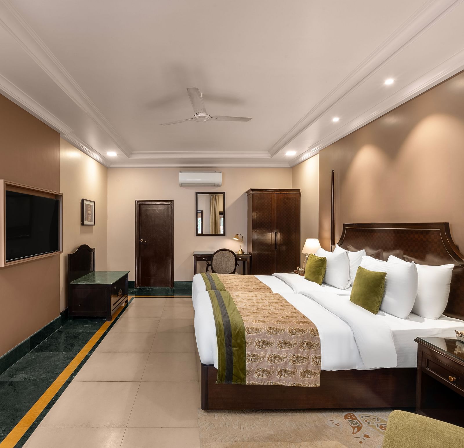 Ganga View Room with a side drawer and side lamp, a workdesk and a large bed facing a television - Ganga Lahari, Haridwar
