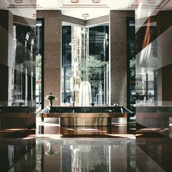 A modern, dimly lit hotel lobby or bar area with stylish furniture and reflective surfaces.