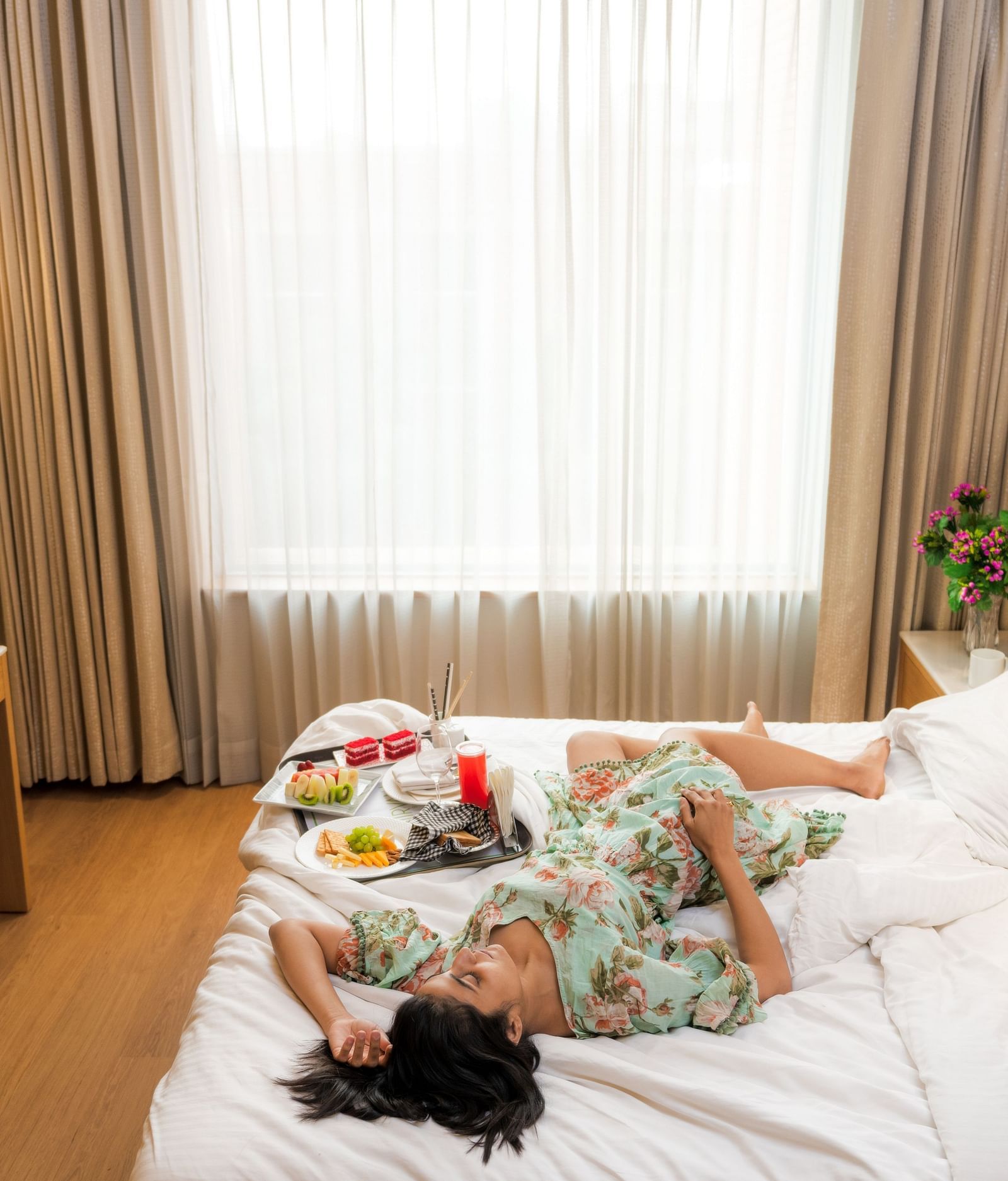 A photoshoot of a woman lying on a bed with a breakfast platter in a room at Nirvana Luxury Hotel, Ludhiana.