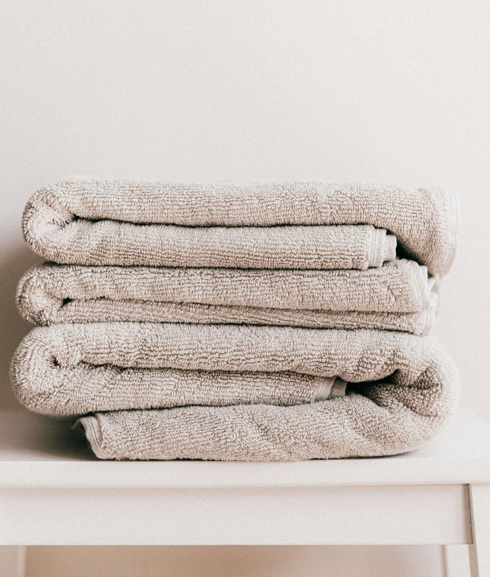 image of fresh white coloured towels neatly folded and kept on a white stool