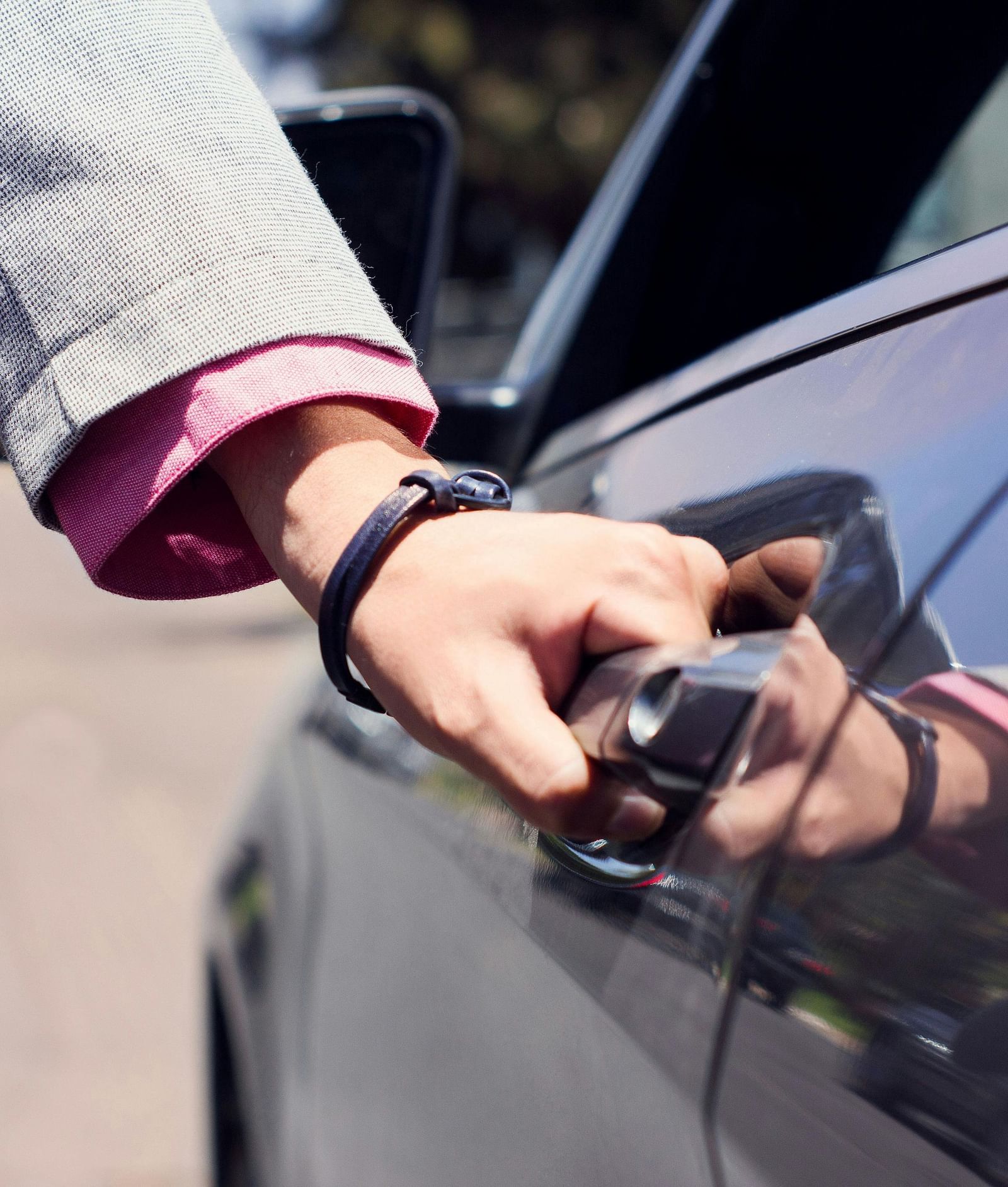 image of a person opening the door of a black coloured car