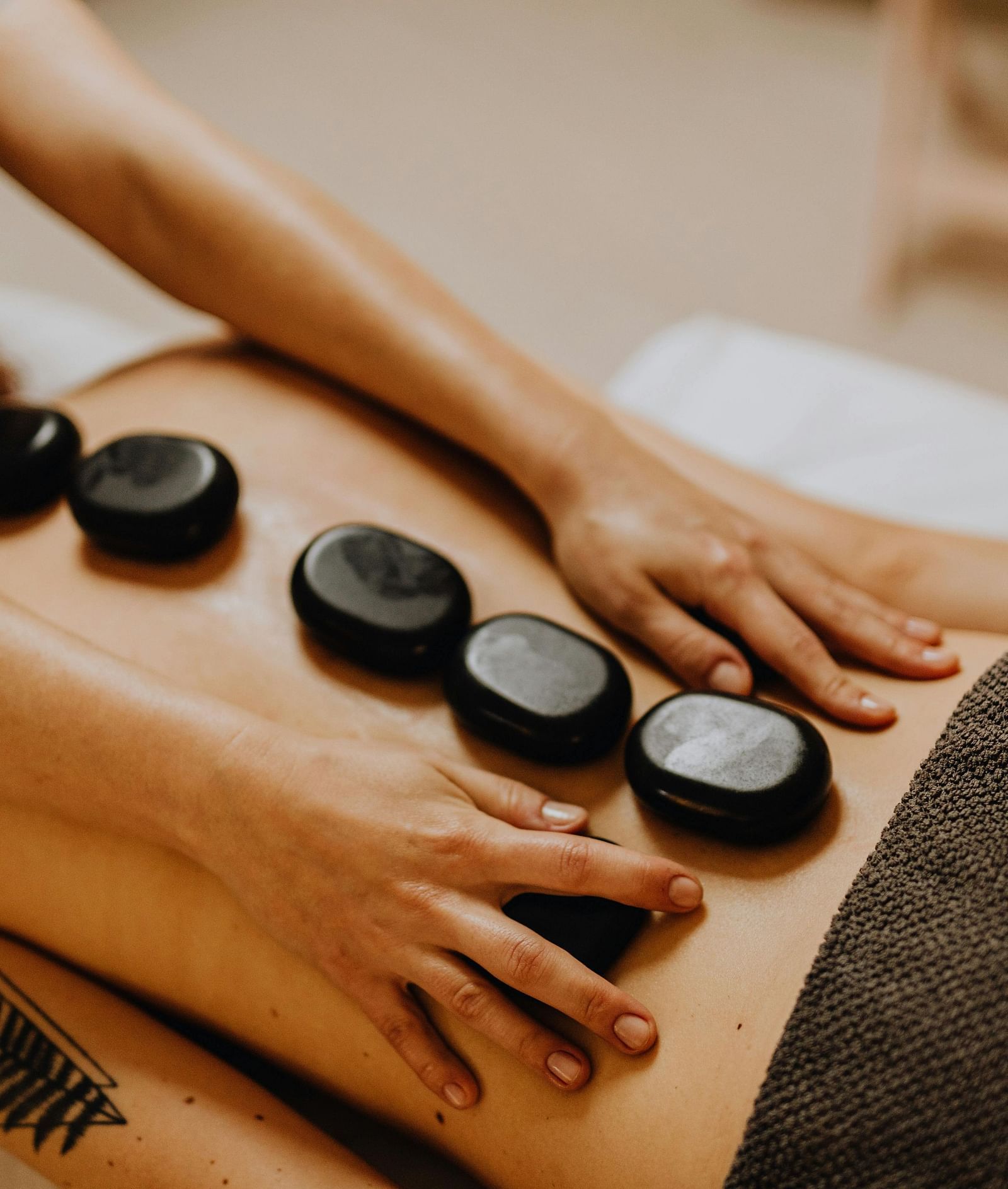 Hot stones placed on a person’s back who is lying down on a flat surface.
