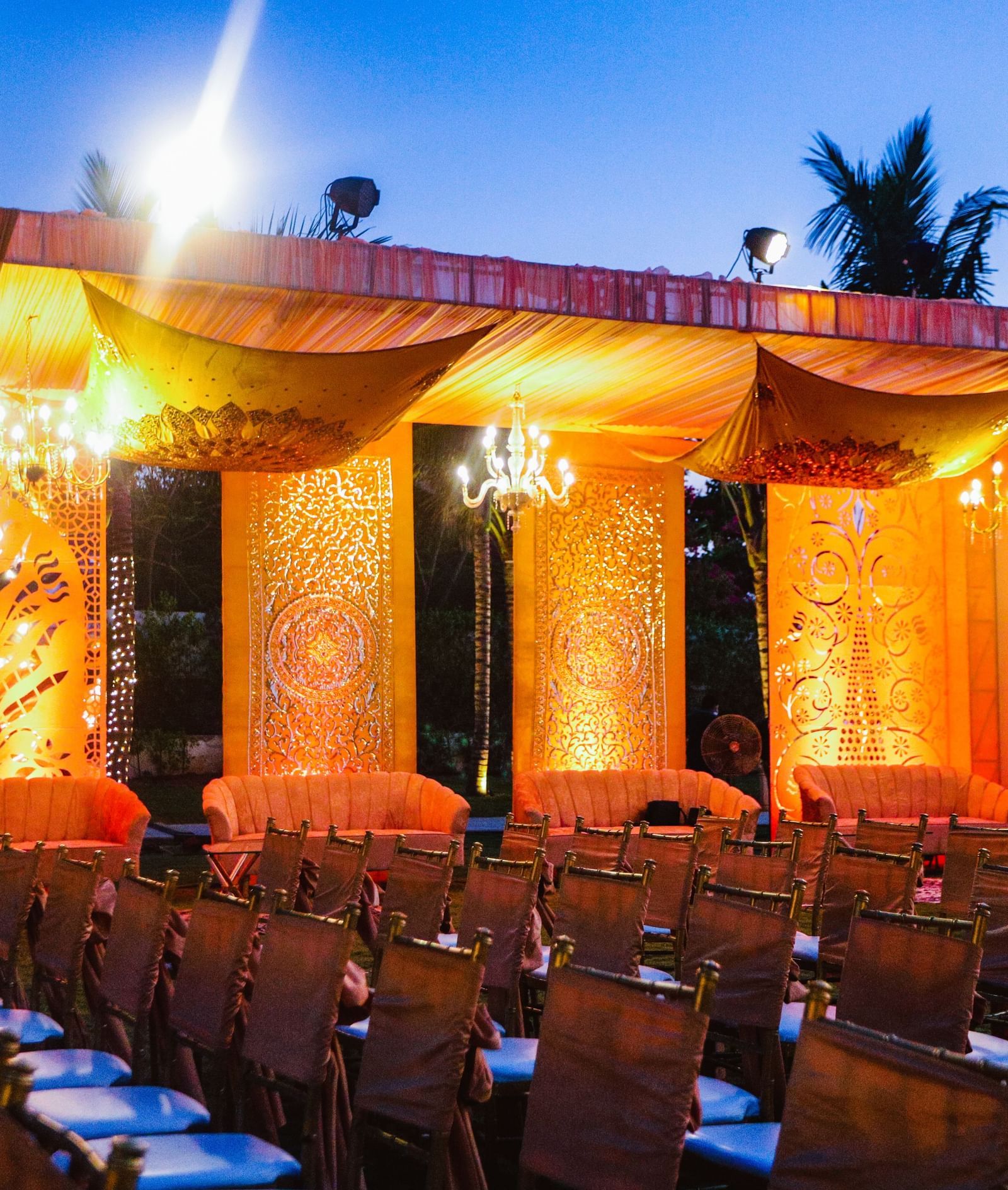 A stage draped with orange coloured cloth in the Sundarabagh lawn at Kaldan Samudhra Palace featuring chairs in theatre seating arrangement