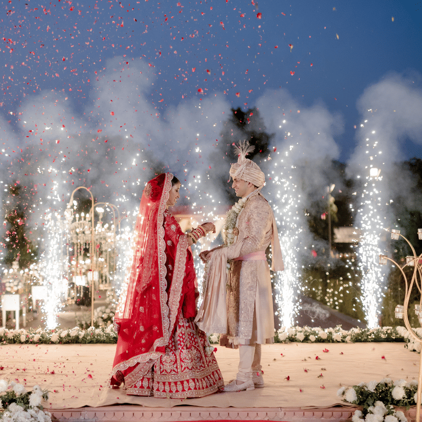 Bride and groom making a grand entrance with fireworks during a night wedding at Umaid Palace.