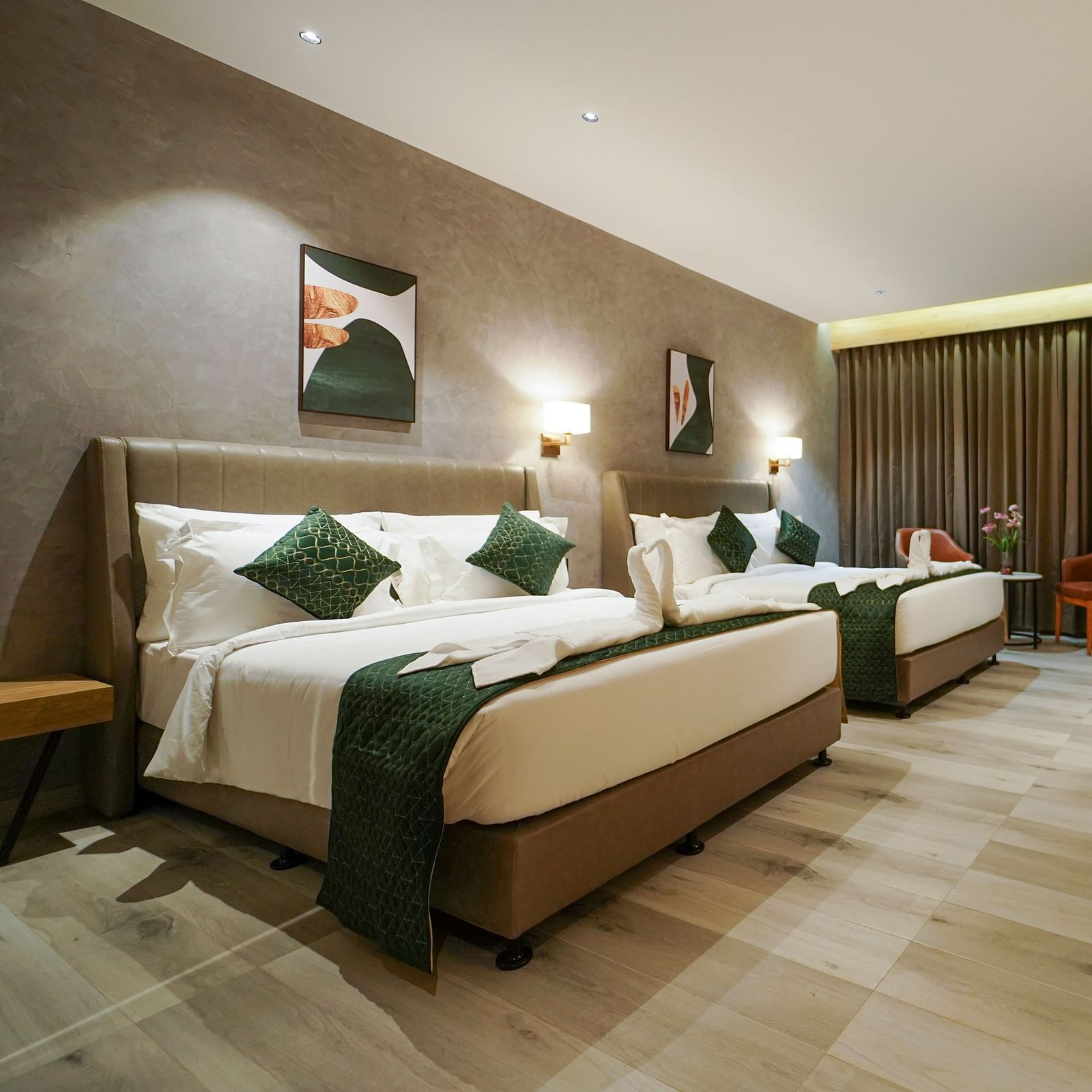 A hotel room contains two beds with decorative linens and pillows, a desk area with a lamp and chair, and window curtains - Hotel Park Inn, Nellore.