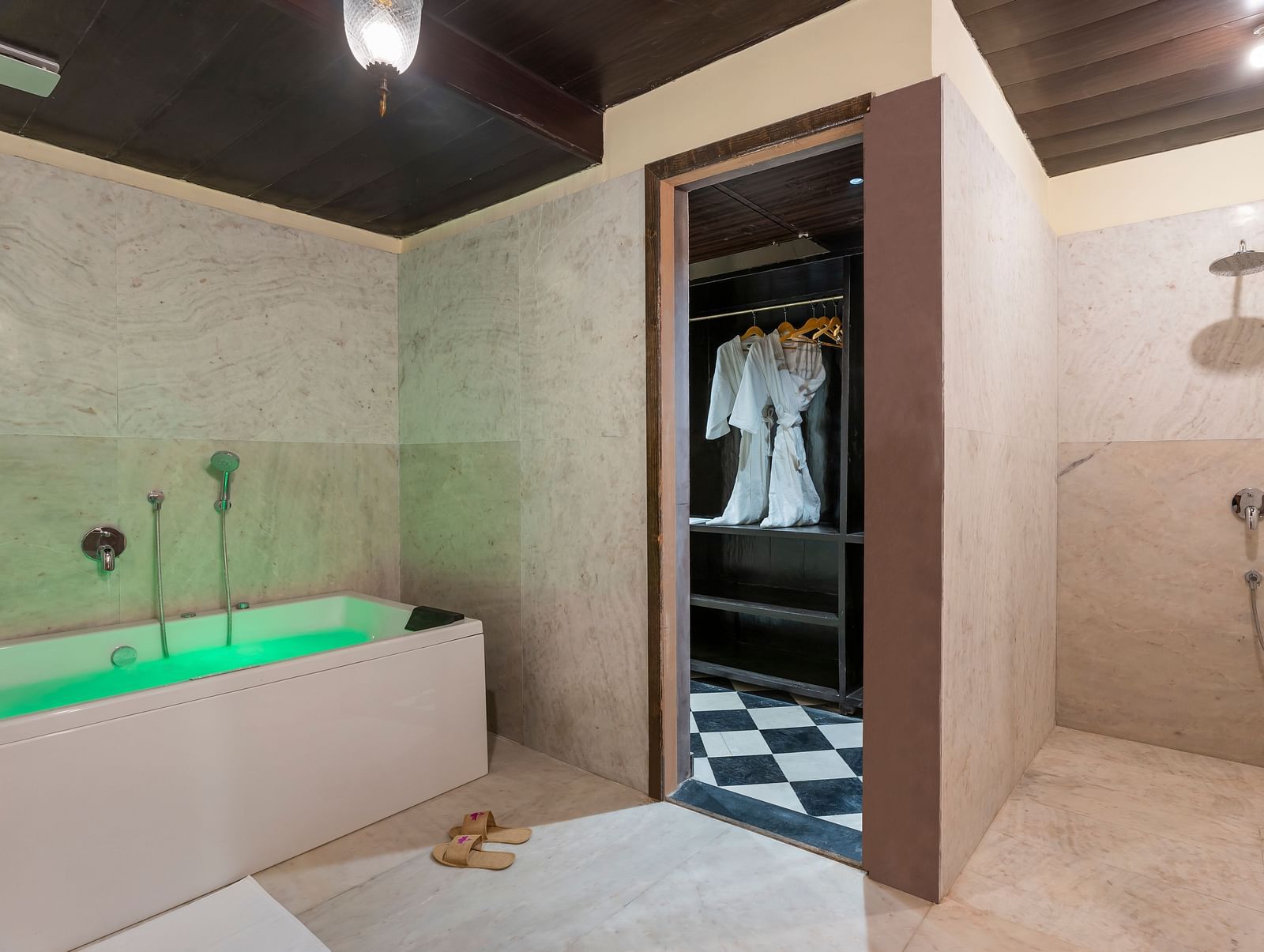 Luxurious bathroom with green bathtub, open closet, and rain shower at Kesar Bagh Palace.