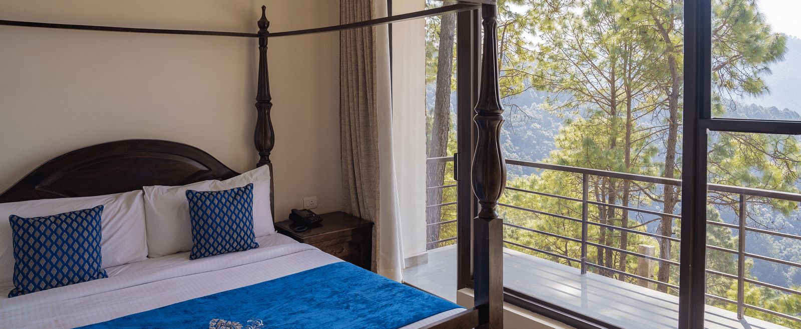 A bed with antique wooden pillars and a balcony next to it at BluSalzz Escapade Resort, Lansdowne