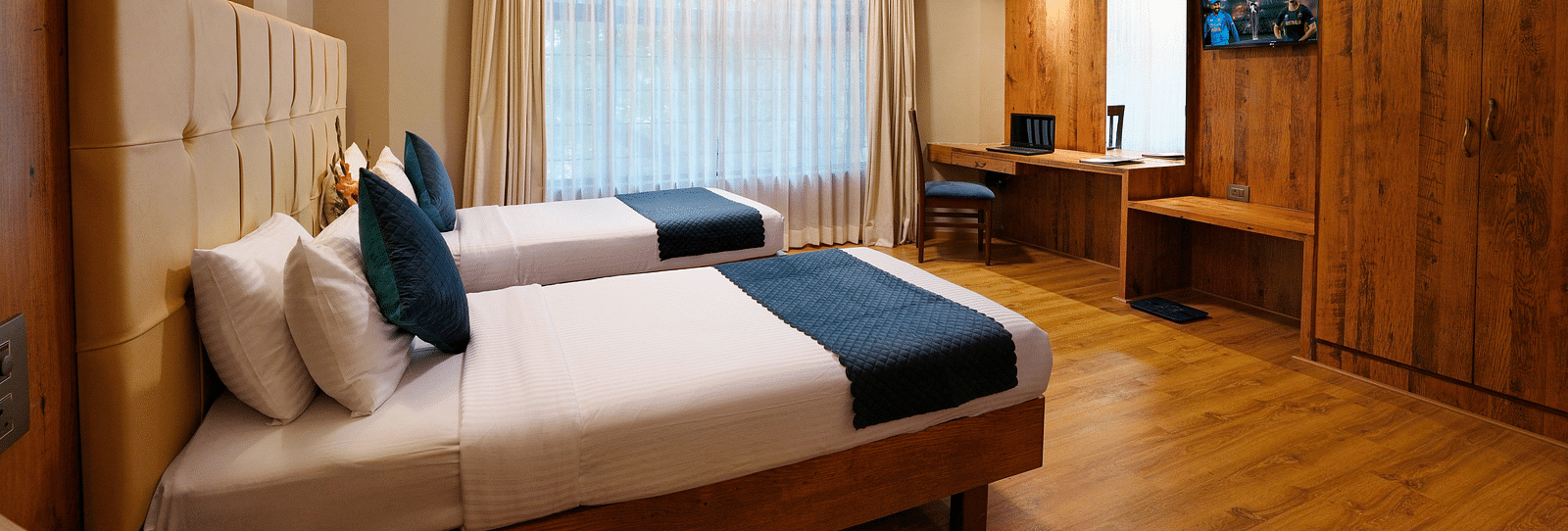 An elegant room featuring twin beds and wooden furnishings - Cross Roads Inn, Bengaluru