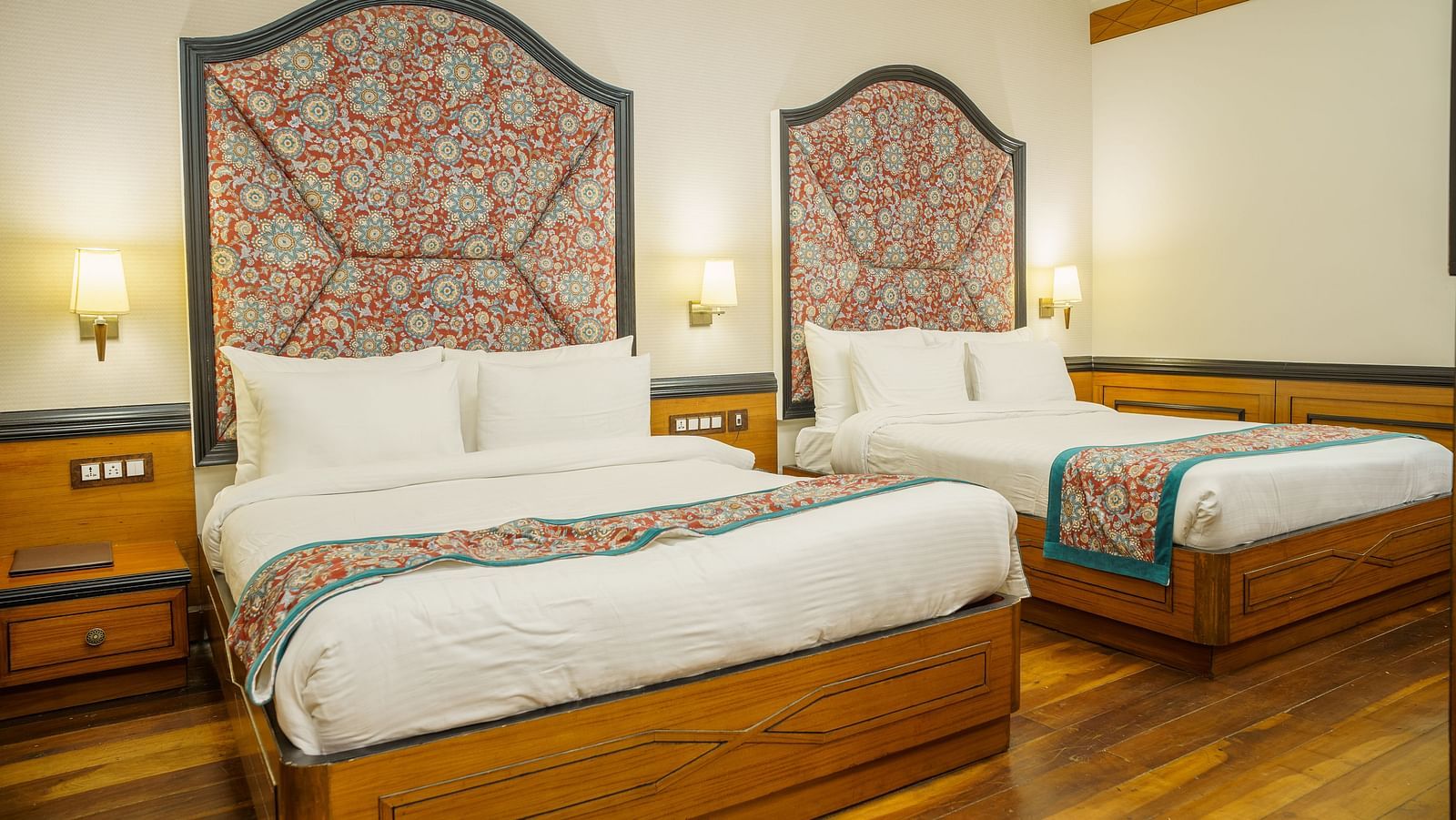 A room at Orsino Spa Resort with two beds, each with a distinctive patterned headboard and a colourful throw.