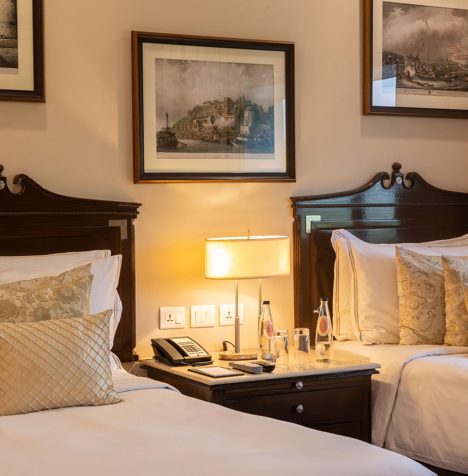 Grand Luxury Twin Bed Room at The Claridges New Delhi, featuring elegant twin beds, framed photos on the wall, and a bedside lamp placed between the beds