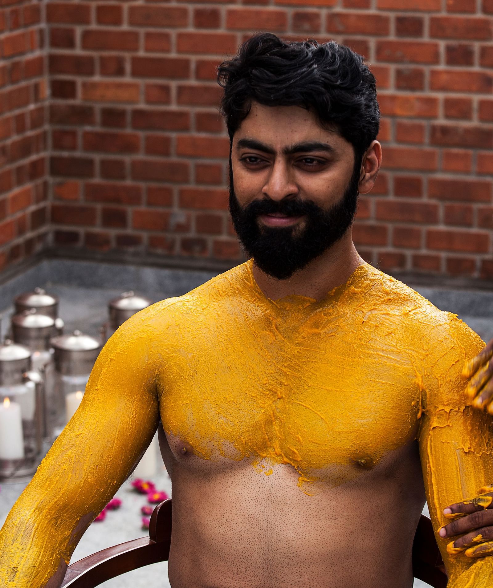 A person with yellow markings on their body, brick wall background - Shreyas Retreat