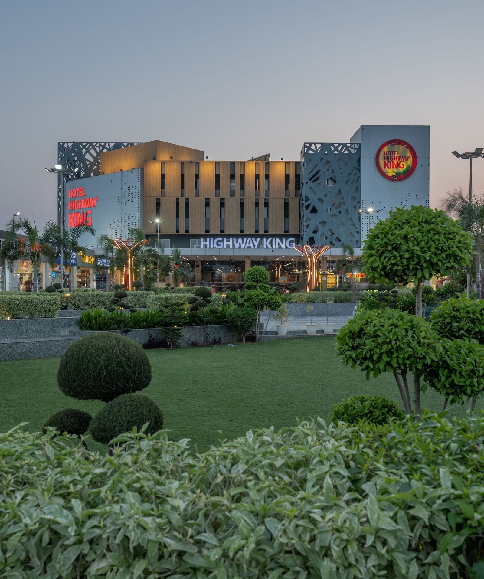 Neatly landscaped garden with evening view of Hotel Highway King, Bilaspur, in the background.