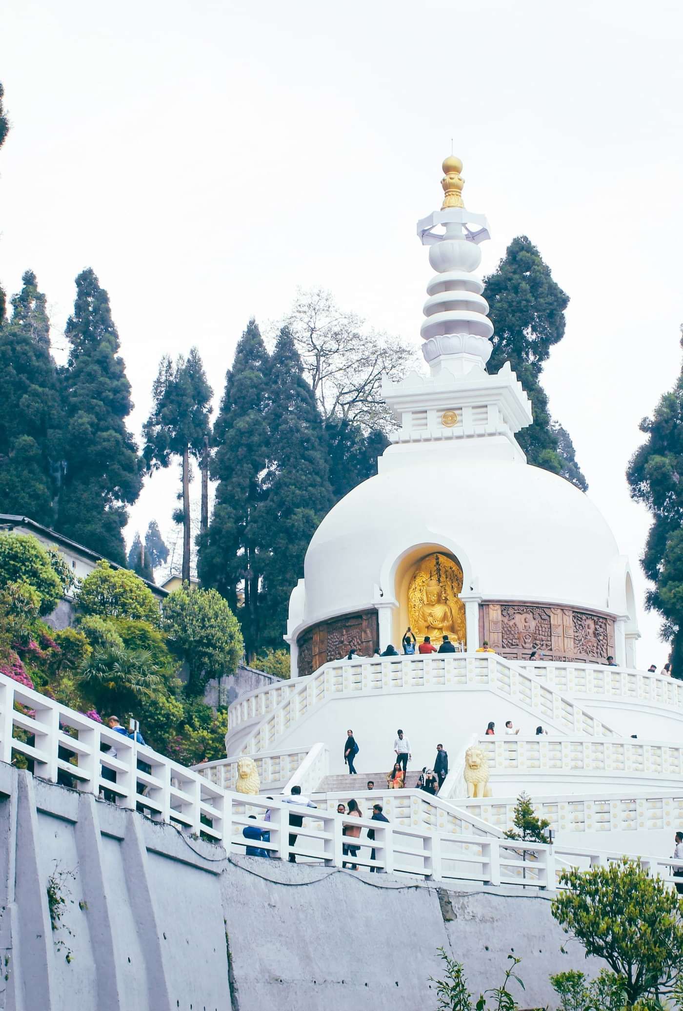 Japanese Peace Pagoda surrounded by lush gardens, standing tall against a backdrop of green trees.