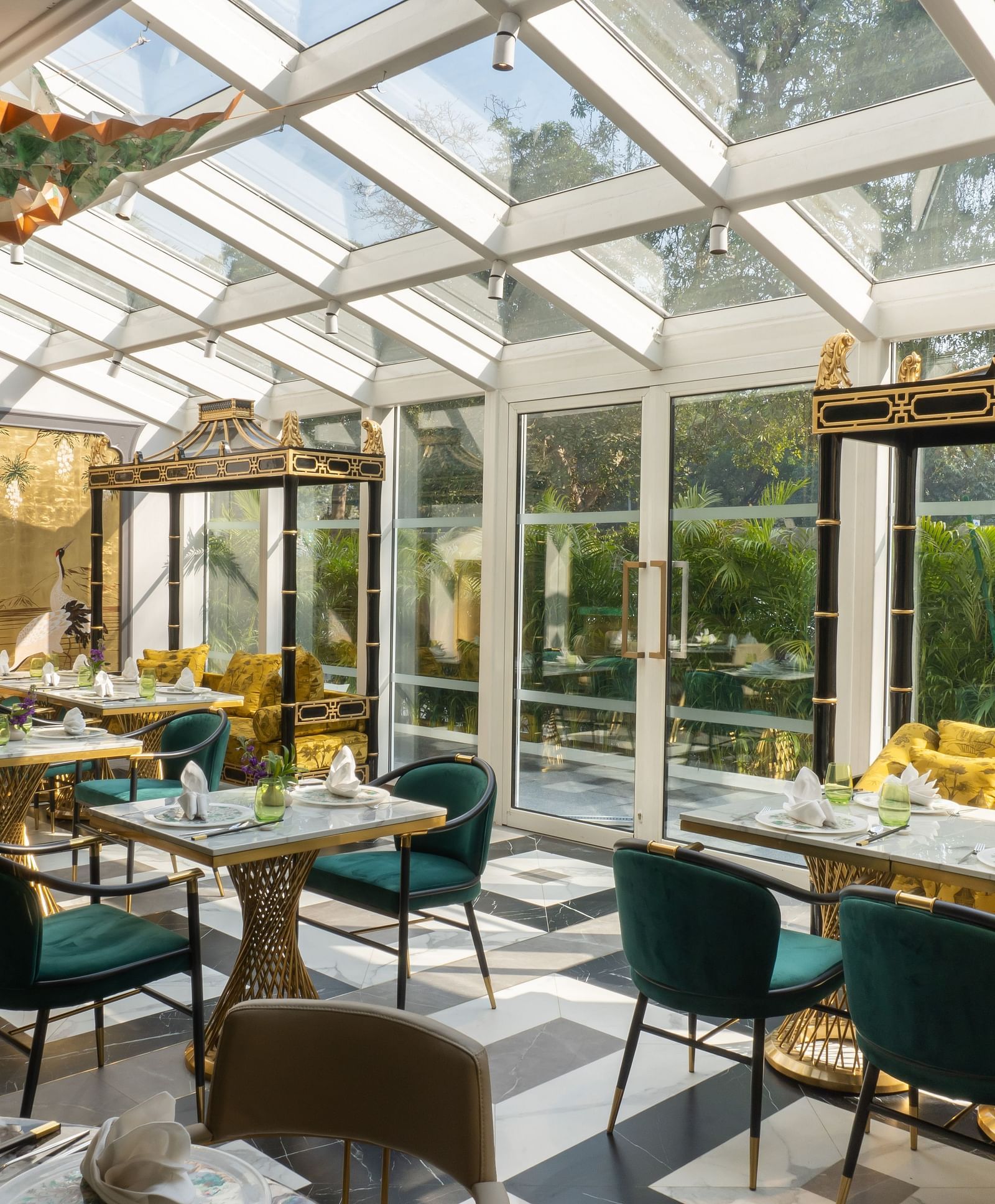 Image featuring the Jade dining section at The Claridges New Delhi, offering elegant seating arrangements beneath a glass rooftop with a direct view of the sky