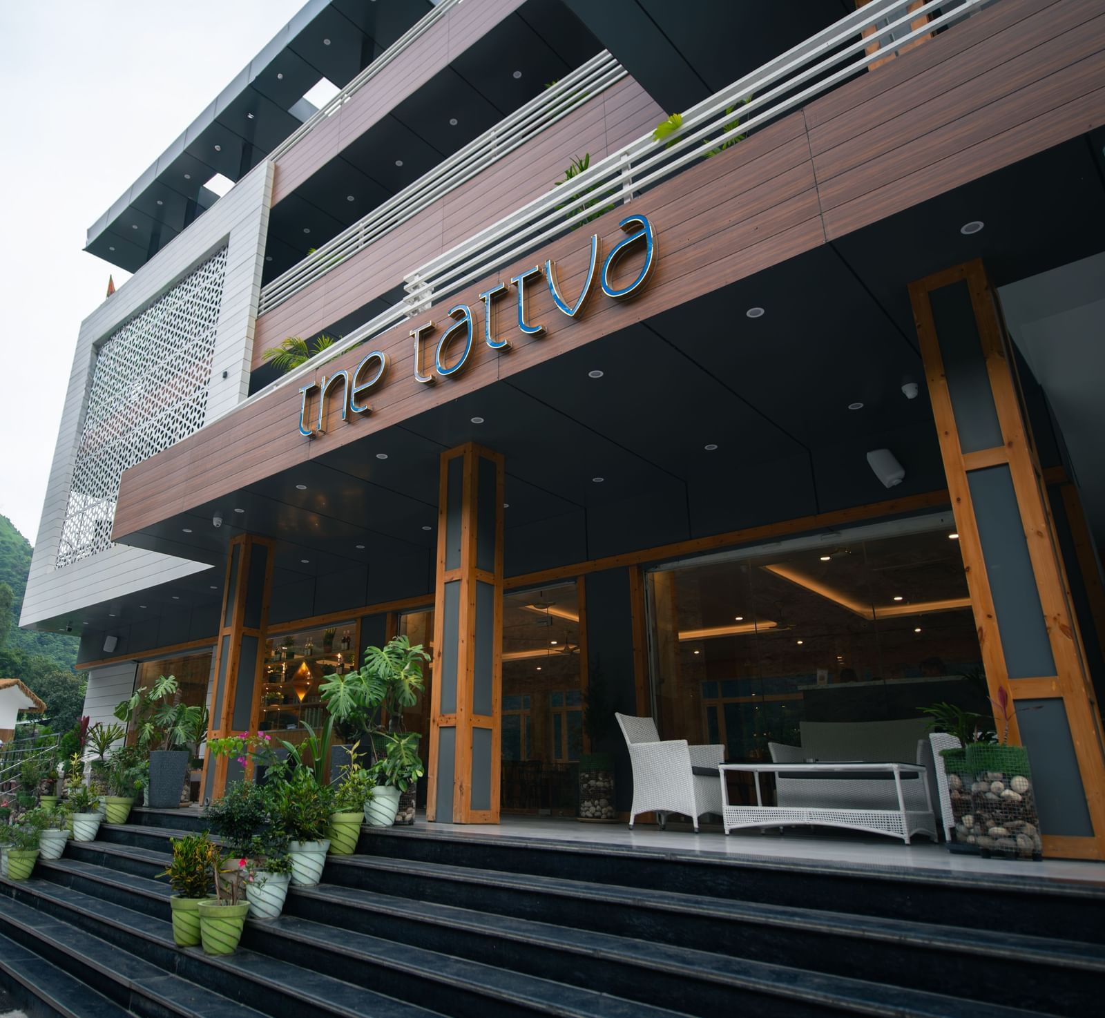 Facade of The Tattva Devaprayag hotel featuring the entrance and three floors.