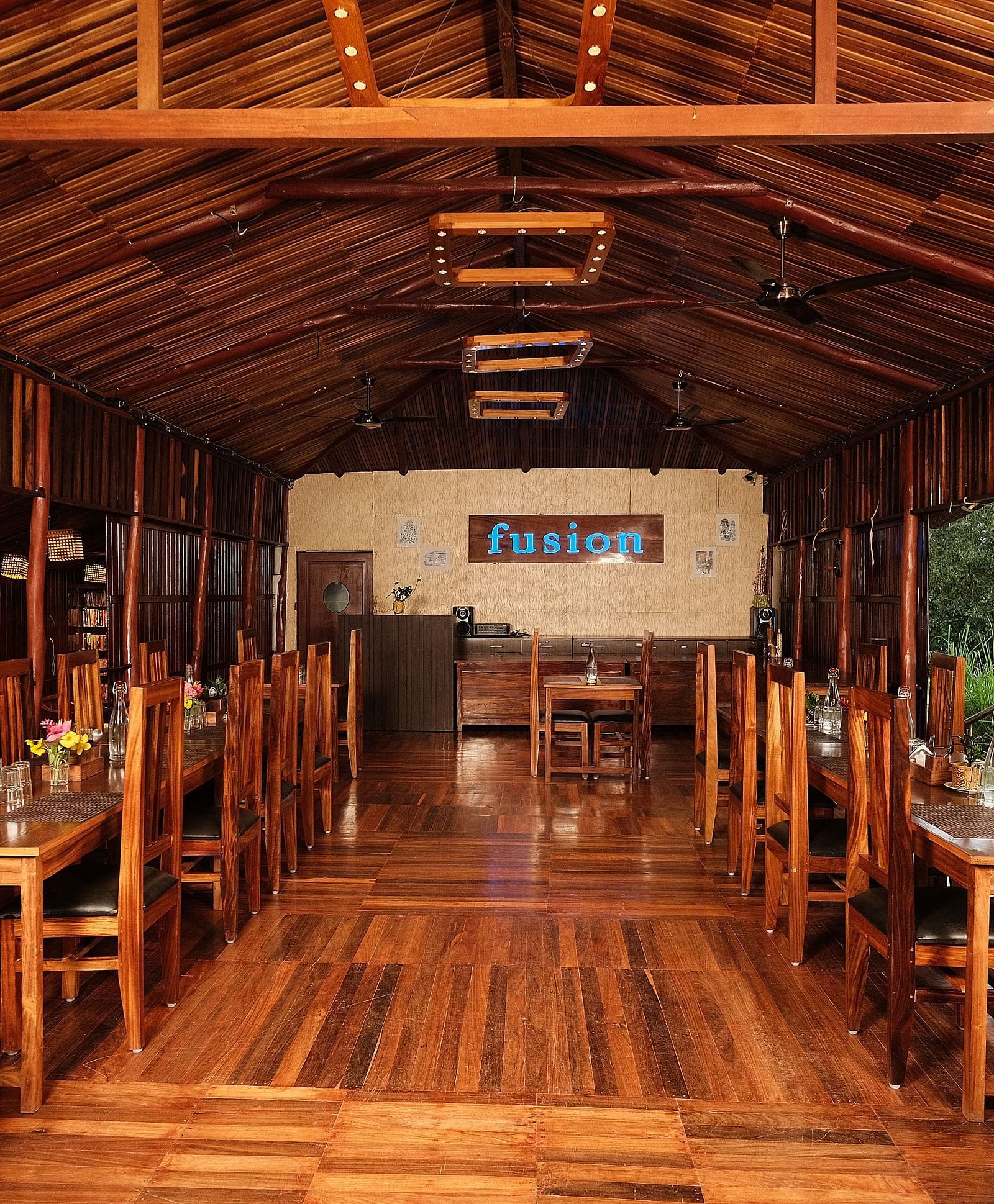 The interior of a wooden restaurant with tables and chairs | Fusion Cafe and Multi-cuisine | RainForest Resort, Port Blair, Andaman and Nicobar Island