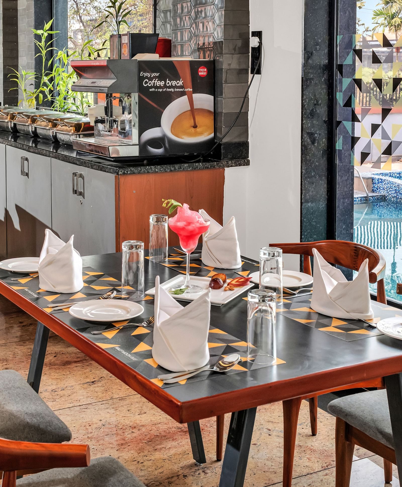 A restaurant dining area with set tables and chairs, overlooking a swimming pool through a glass wall  | The Citi Residenci Hotel Banskopa