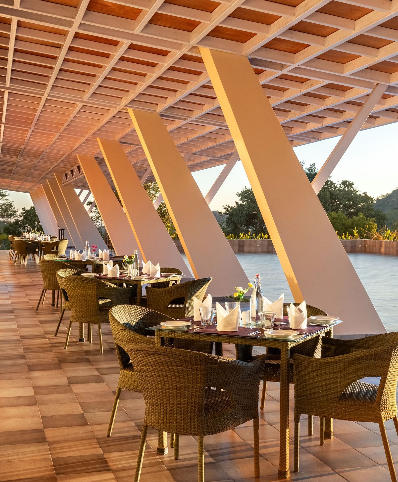 Outdoor dining area with sloped roof, tables, chairs, and a scenic view - Via Lakhela Resort & Spa