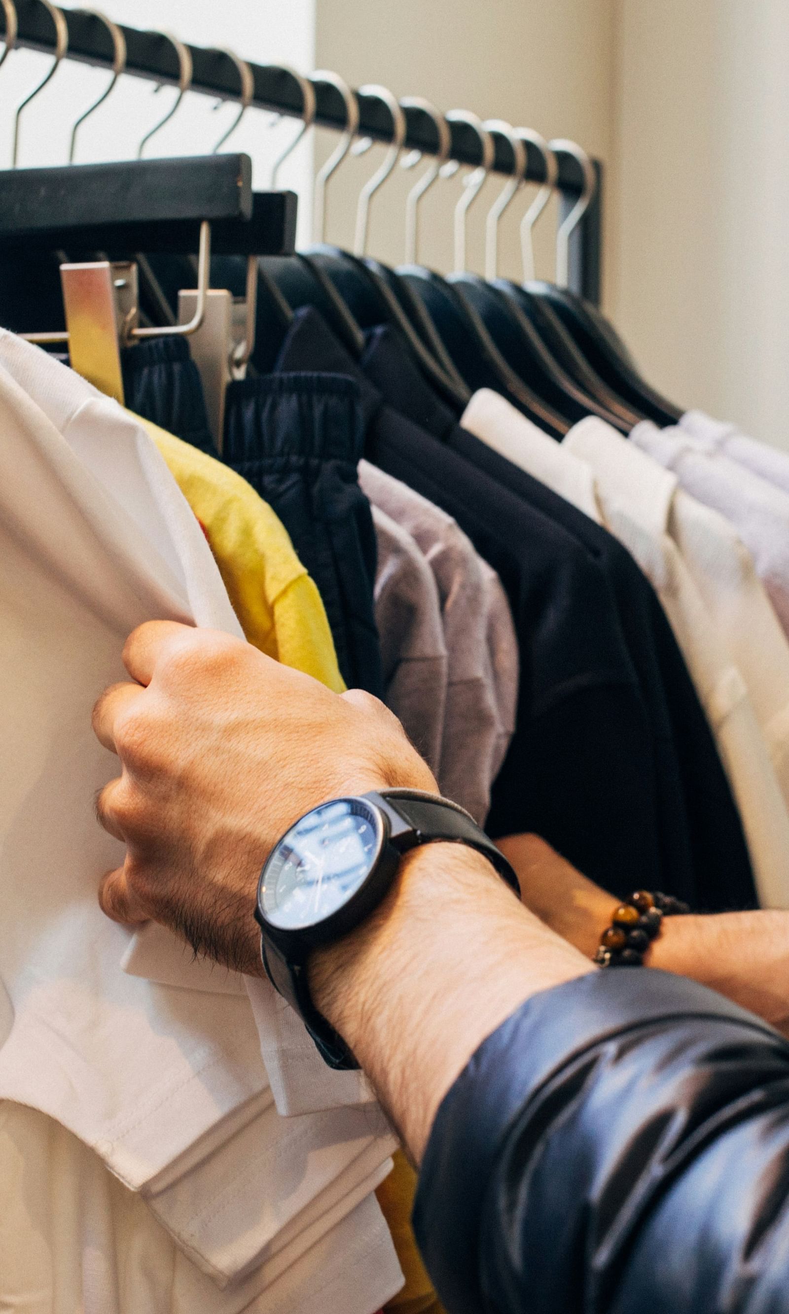 A woman sifts through a rack of clothes, fingers grazing fabrics