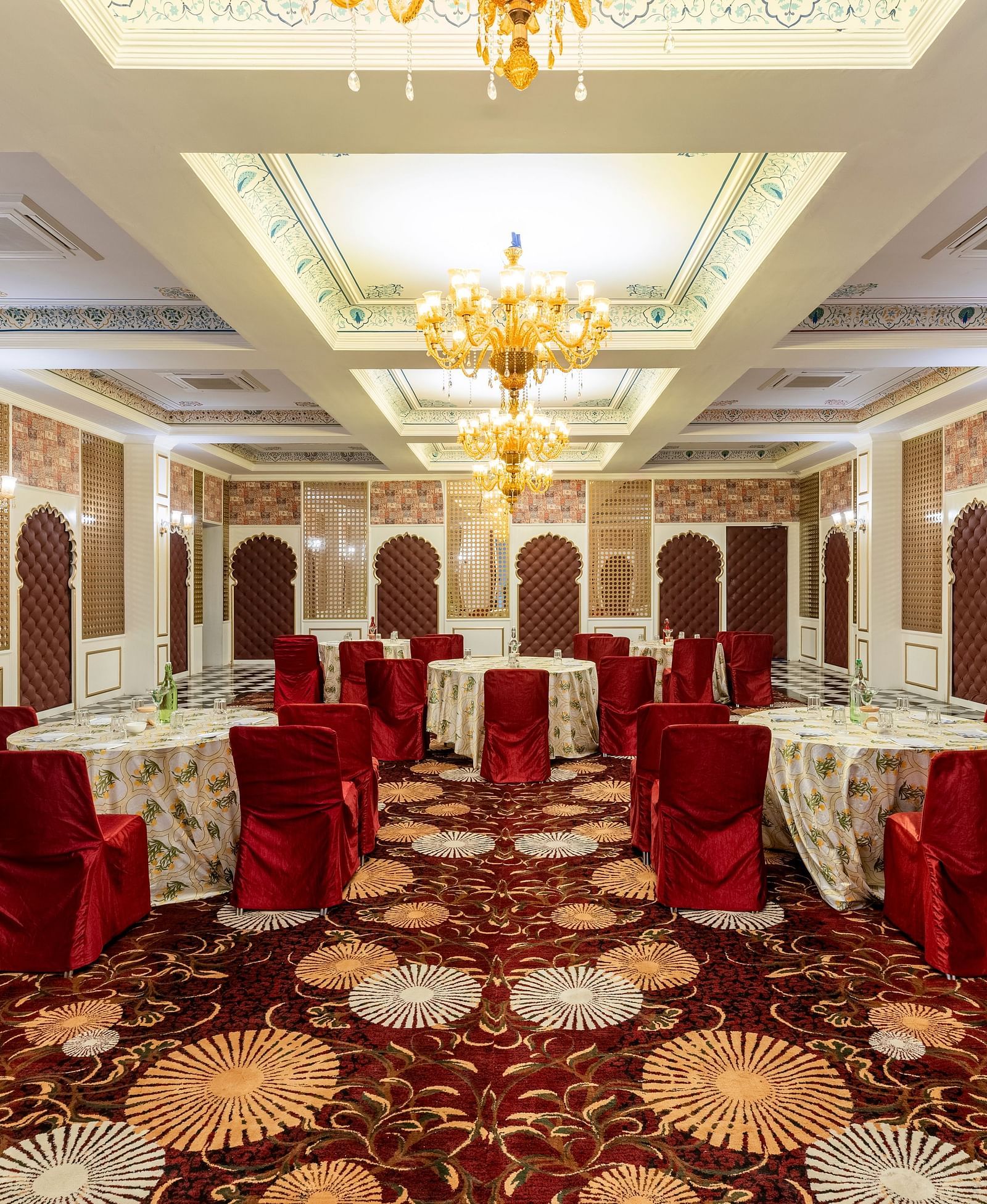 Luxurious banquet hall with red chairs and ornate ceiling at Kesar Bagh Palace.