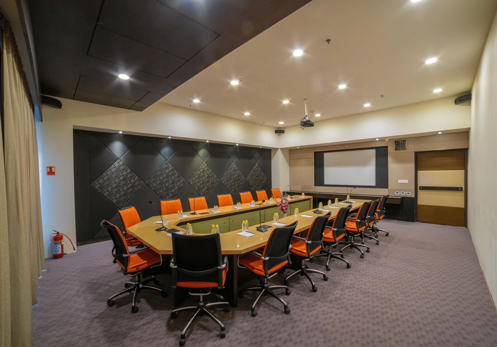 Conference room with a long table, orange chairs, and presentation screen at Narayani Heights Hotel & Resorts, Ahmedabad.