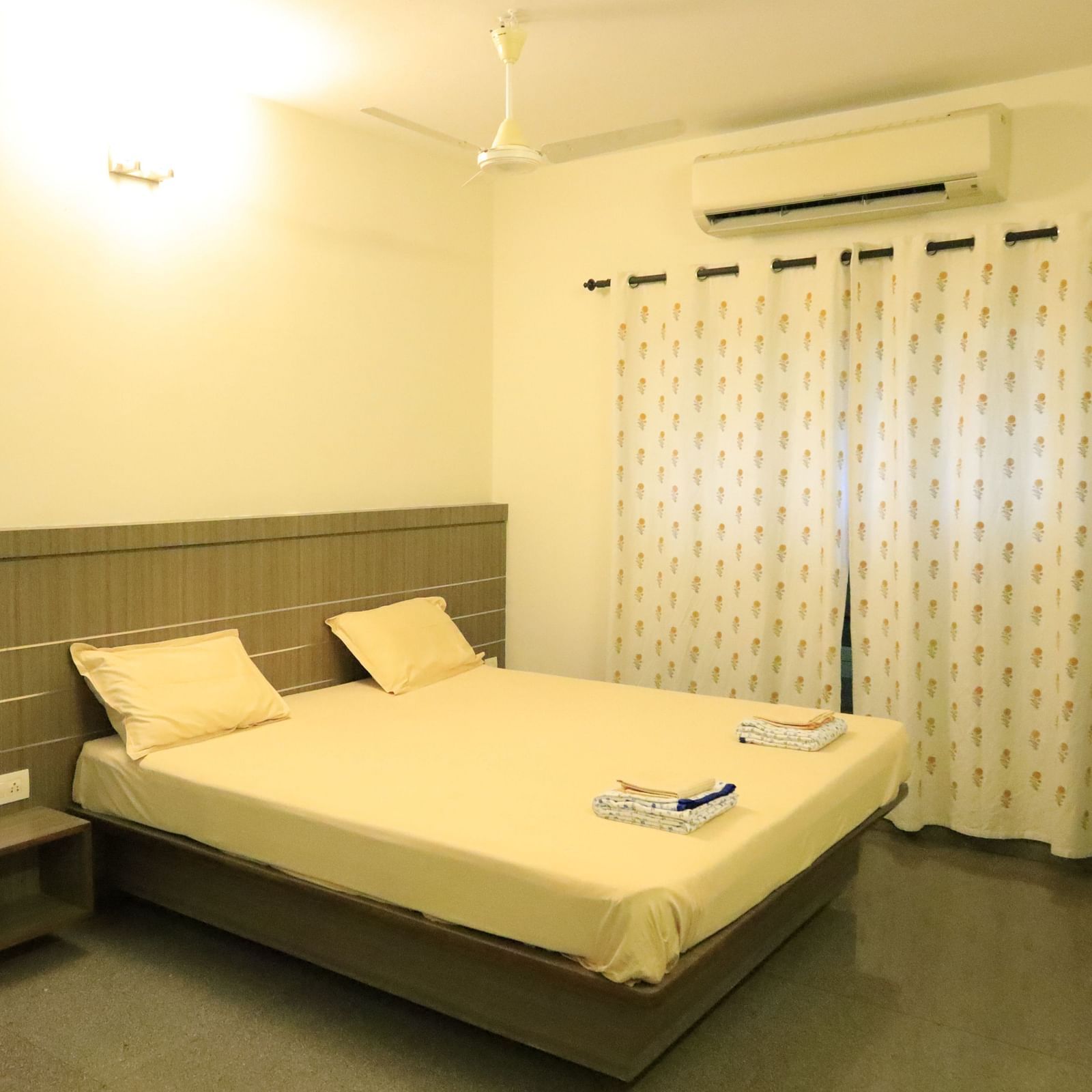 A well-lit bedroom with a comfortable bed with a head board and curtains.
