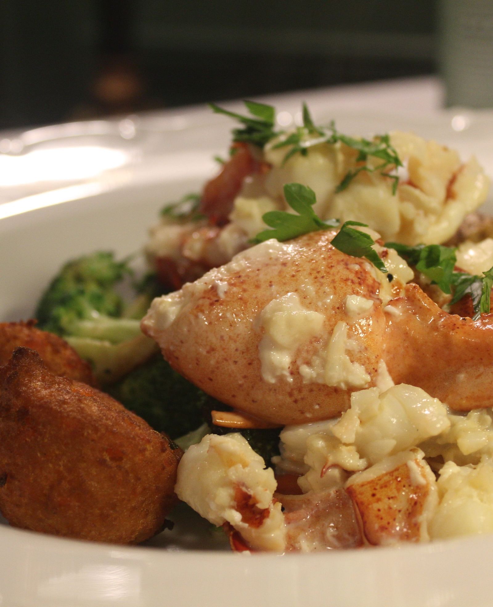 Lobster dish with vegetables on a round white plate.