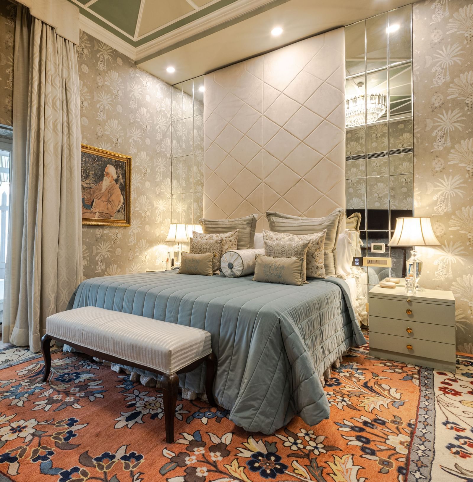 Luxury Suite with Whirlpool at The Claridges New Delhi, featuring a cosy bed with bedside lamps, a table at the foot of the bed, and a large window
